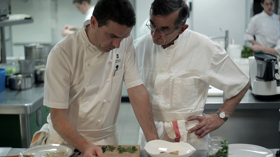 Sébastien focuses on whipping up culinary magic, while enduring father Michel’s whithering gaze. (www.twi-ny.com)